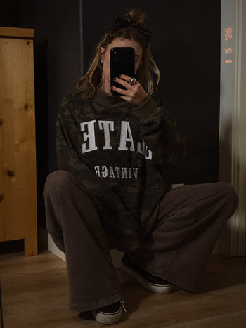 Person wearing a dark hoodie with Slater Vintage , sitting in a dimly lit room.