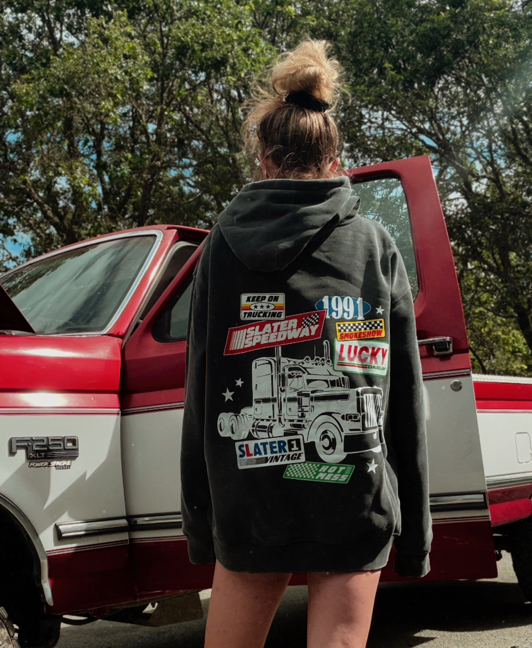 Black hoodie with graphic design on the back featuring a truck and text on a white background