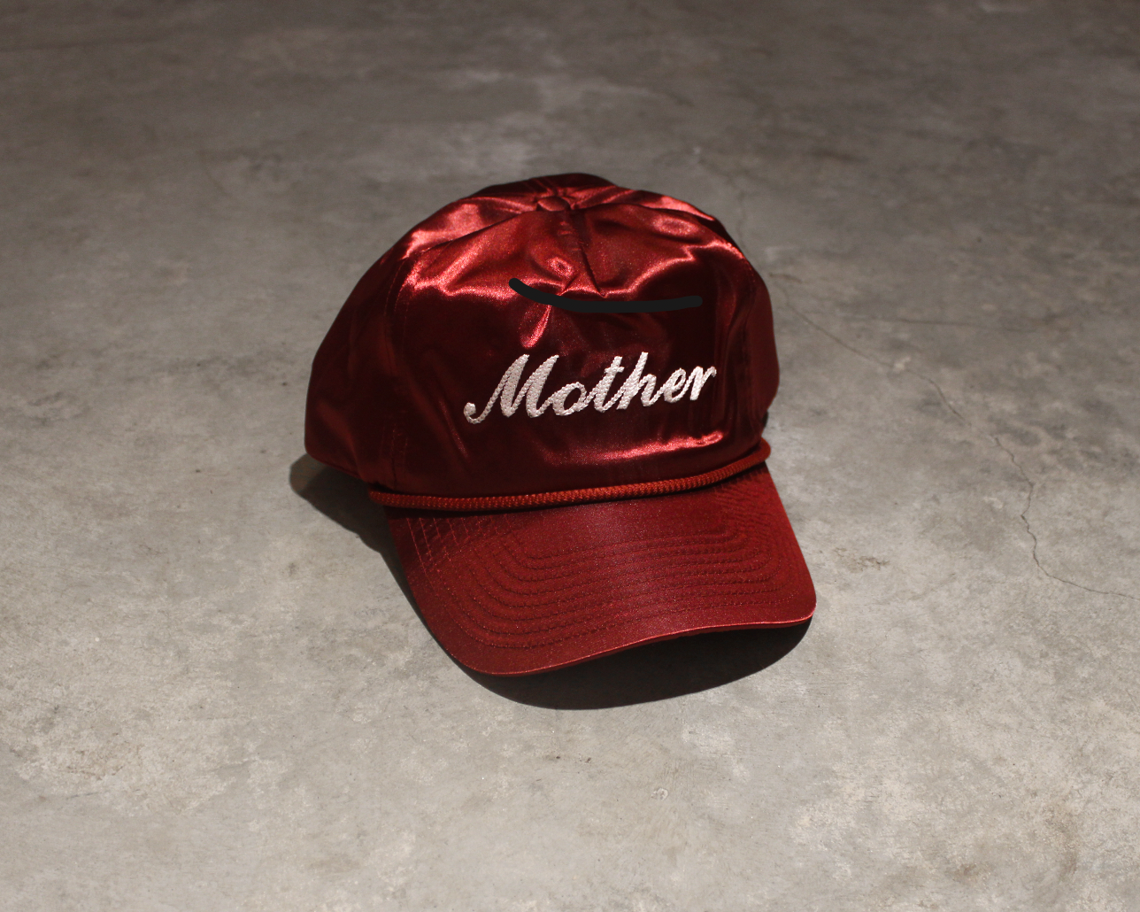satin fabric, cherry cola colored hat sitting on concrete floor 