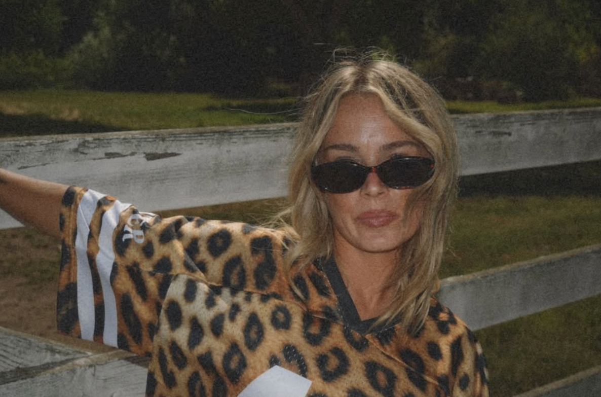 Woman wearing a leopard print outfit and sunglasses sitting on steps outdoors.